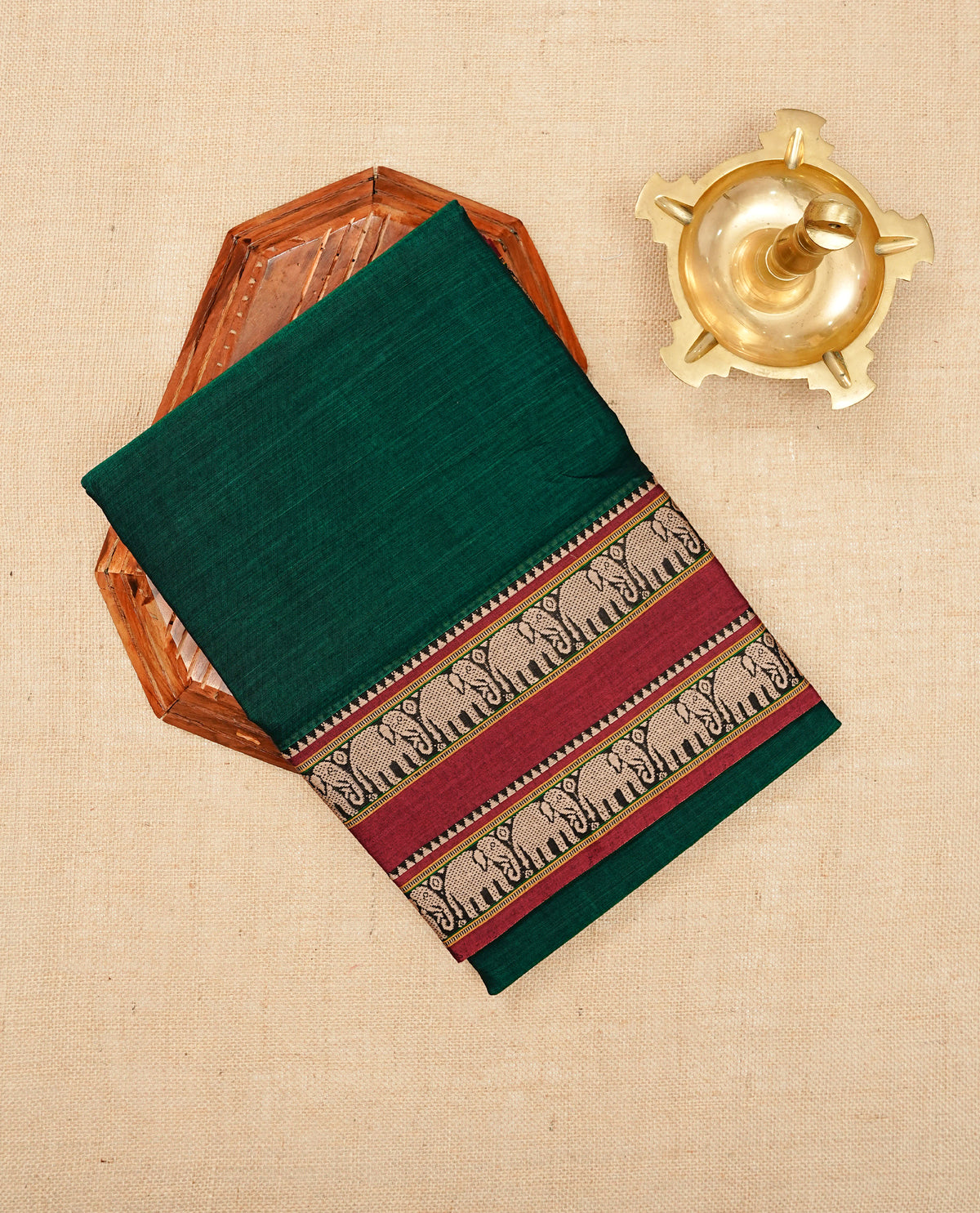 Bottle Green colour Narayanapattu cotton saree with a plain body, complemented by a Maroon Colour with beige colour Elephant designed border & contrast pallu, paired with a matching blouse piece.