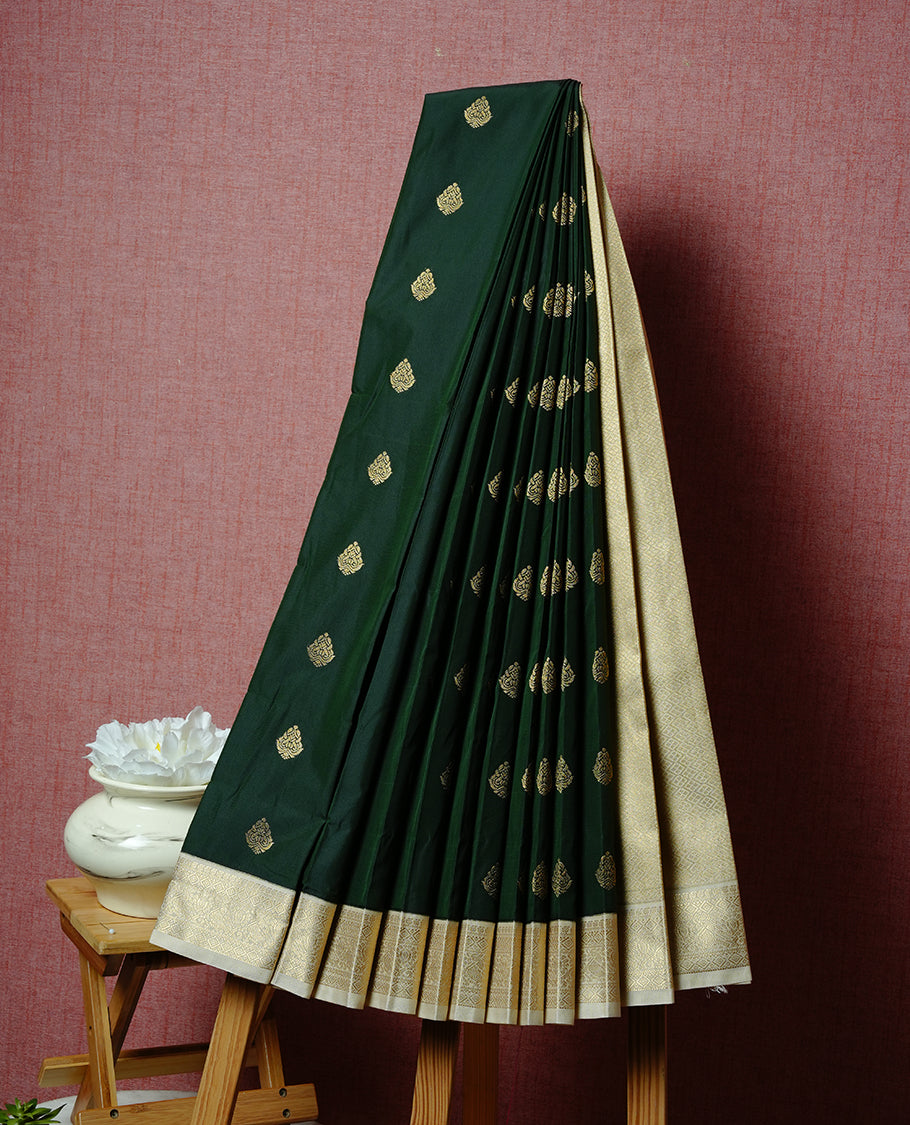 Dark green coloured soft silk saree featuring gold zari motifs across the body, enhanced with a contrast Cream border and pallu, paired with a matching contrast blouse piece.
