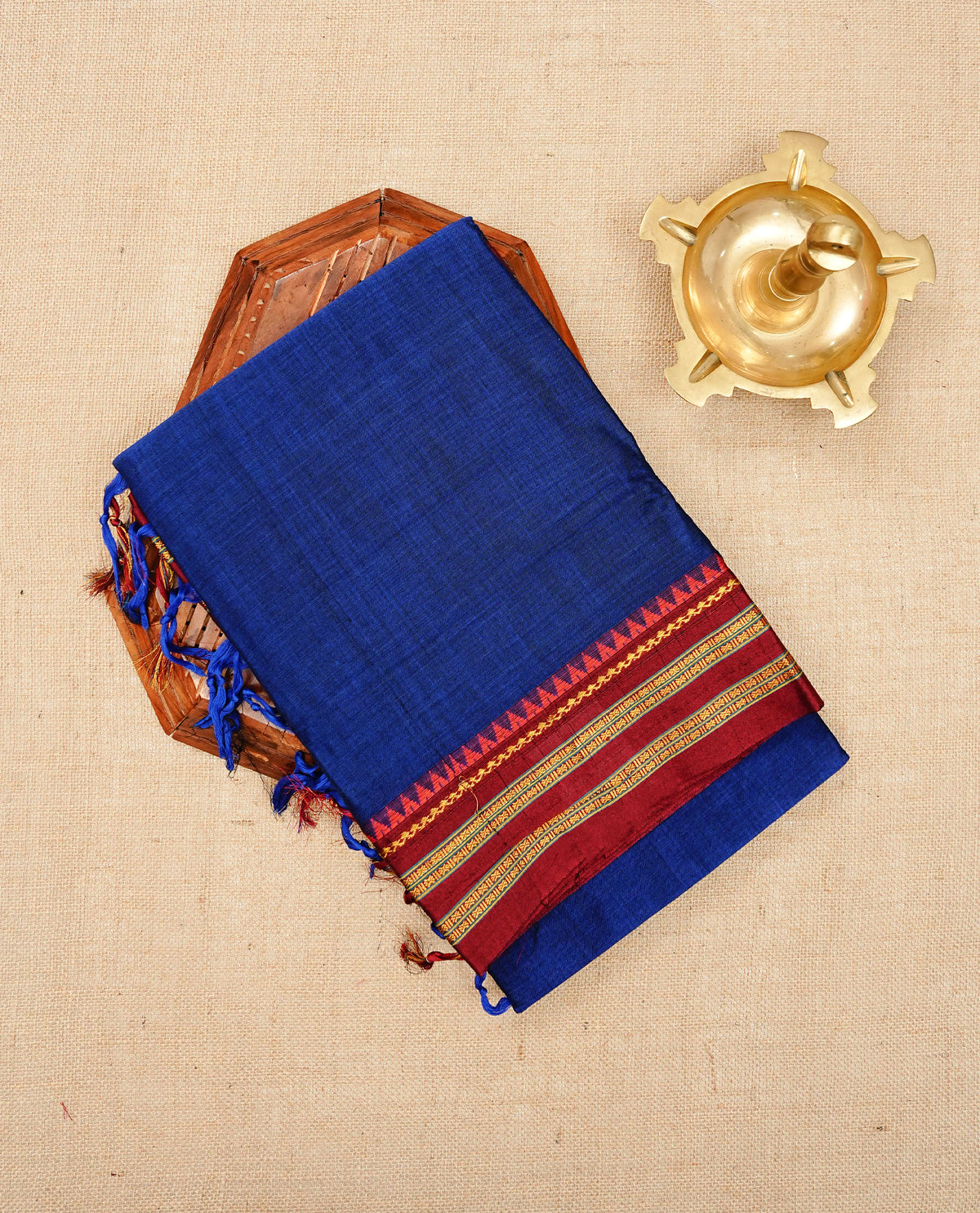 Blue colour Narayanapattu cotton saree with a plain body, complemented by a Maroon colour with elegant gold zari detailing border & contrast striped pallu, paired with a matching blouse piece.