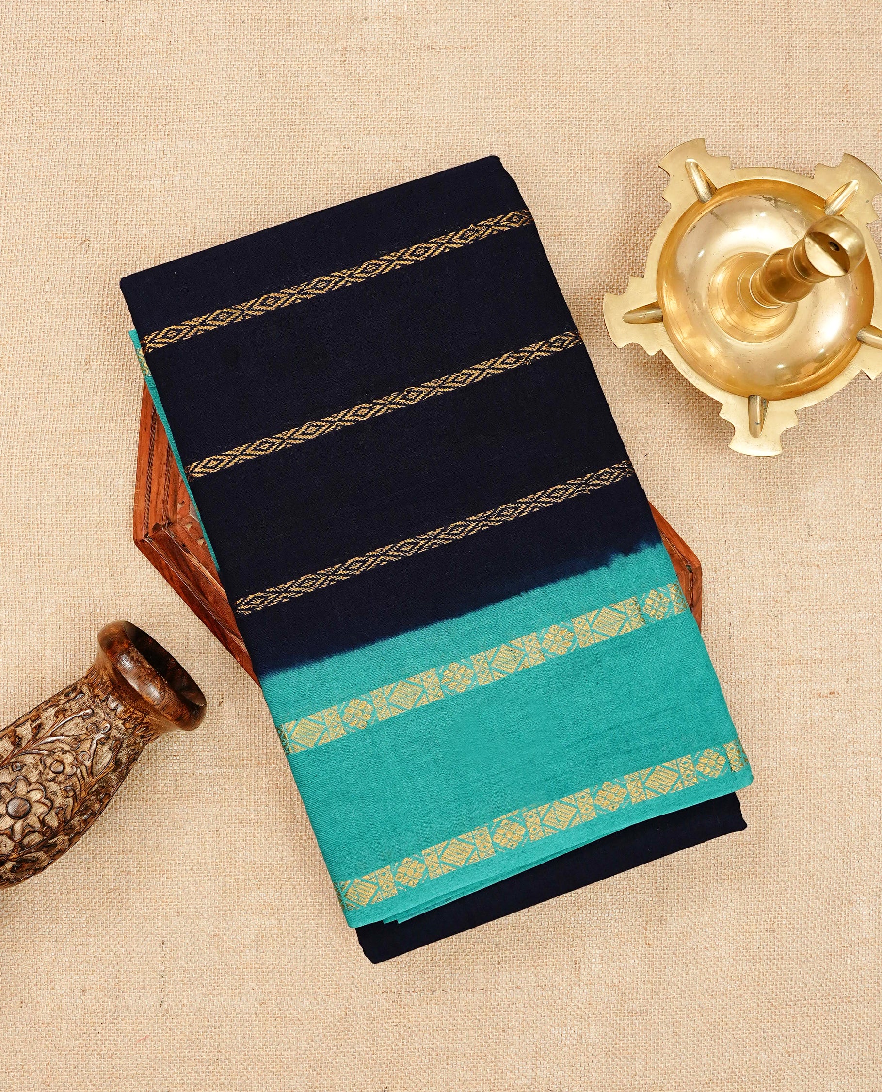 Navy blue colour colour Sungudi cotton saree featuring elegant gold zari stripes on the body, complemented by a contrast teal with gold zari border and pallu, paired with a matching blouse piece