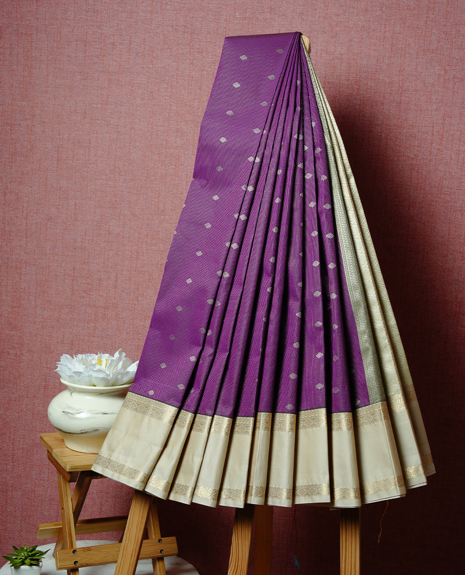 Purple coloured soft silk saree featuring gold zari stripes and motifs across the body, enhanced with a contrast Cream border and pallu, paired with a matching contrast blouse piece.