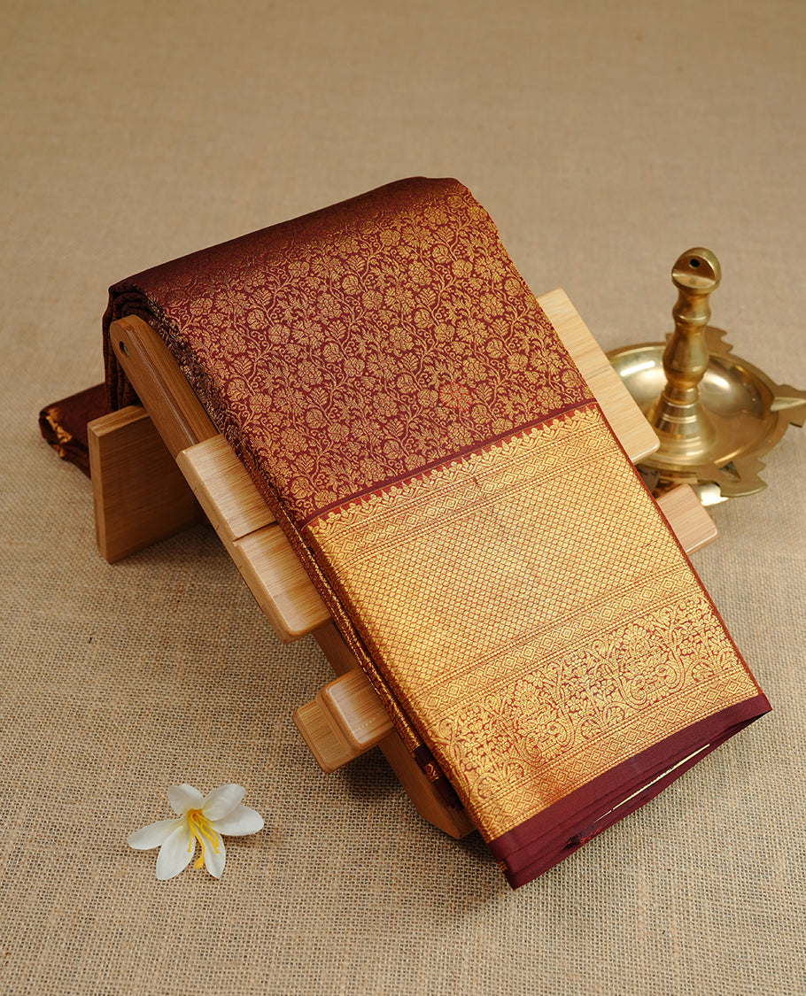 Chocolate colour kancheepuram silk saree featuring gold zari floral kodi pattern on body, complemented by self colour with traditional border, paired with matching blouse piece.