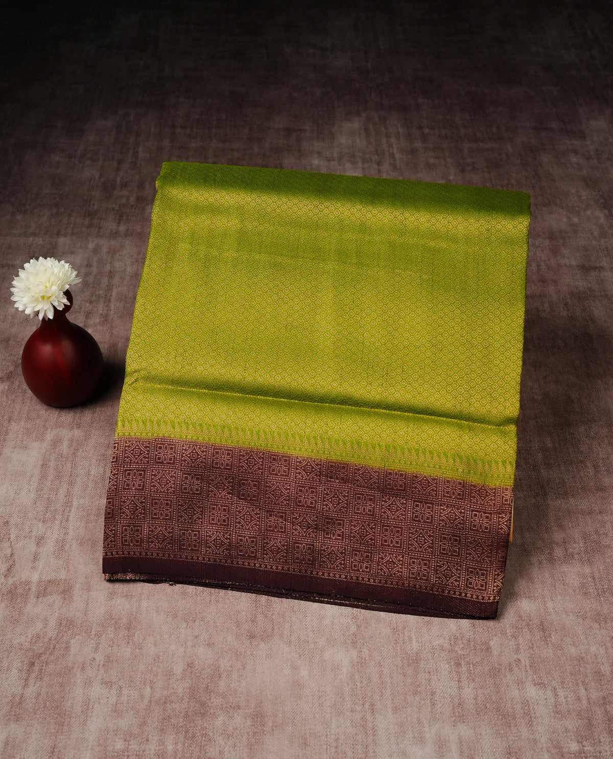 Olive green colour softie silk saree featuring gold zari, rich pallu floral pattern brocade body, with contrasting chocolate colour border.paired with matching blouse piece.