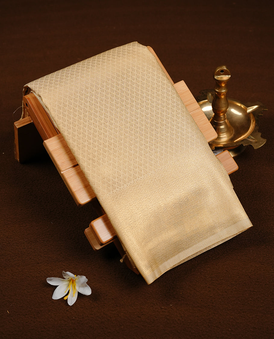 Cream colour soft silk saree featuring gold zari pattern on body, complemented by self colour with traditional border, paired with matching blouse piece.
