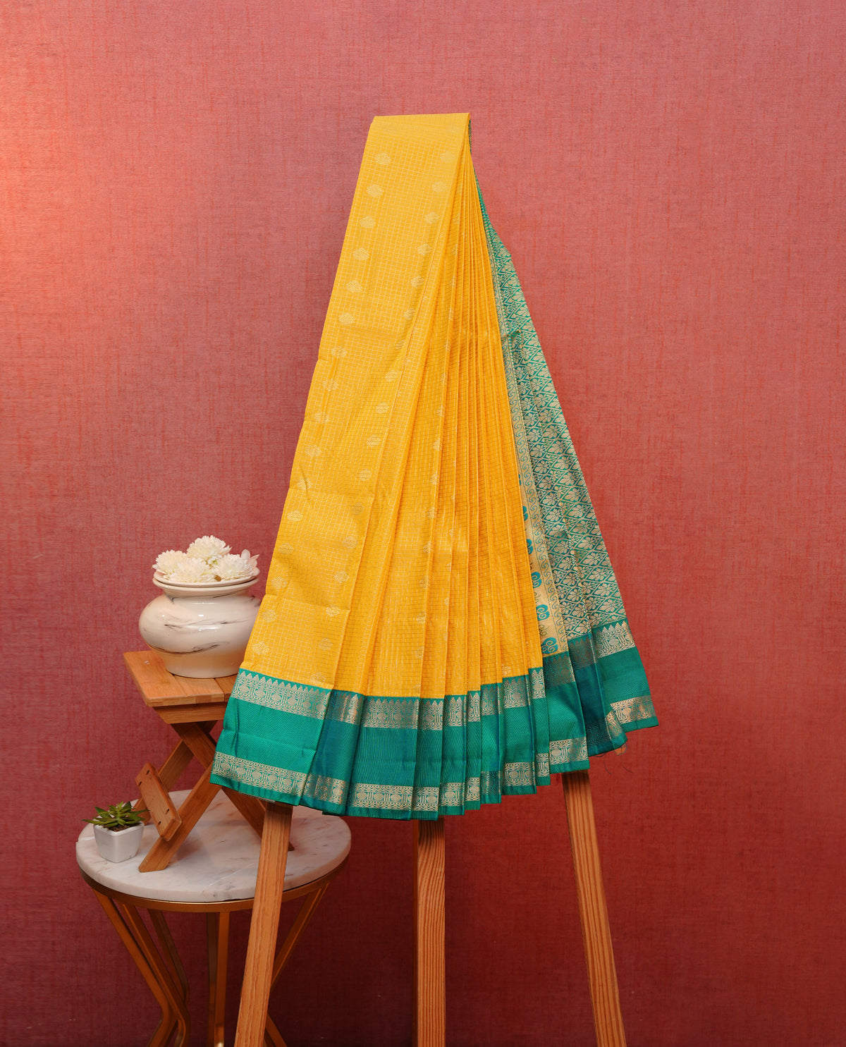 Yellow colour soft silk saree featuring gold zari checks with motifs on body, contrast teal colour traditional border, grand pallu comes with matching blouse piece.