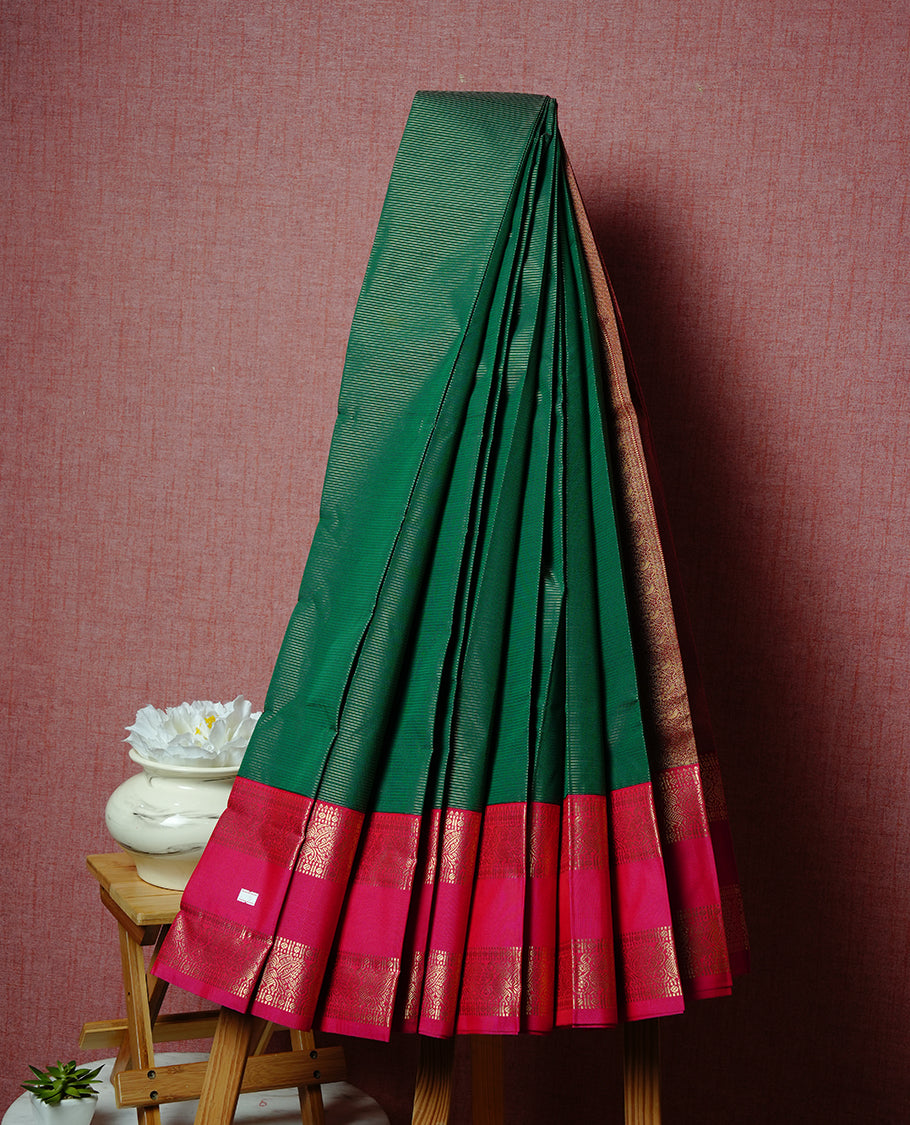 Dark Green coloured soft silk saree featuring gold zari stripes and motifs across the body, enhanced with a contrast Magenta border and pallu, paired with a matching contrast blouse piece