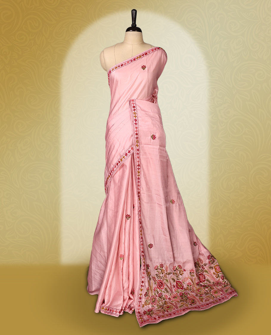 Pink colour pure tussar saree adorned with delicate multicolour floral embroidery along the border and scattered motifs across the body, paired with a matching blouse.