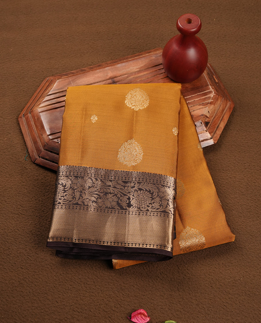 Mustard colour soft silk saree featuring gold zari motifs on the body, complemented by a contrast chocolate brown traditional zari border and pallu, paired with a matching blouse piece.