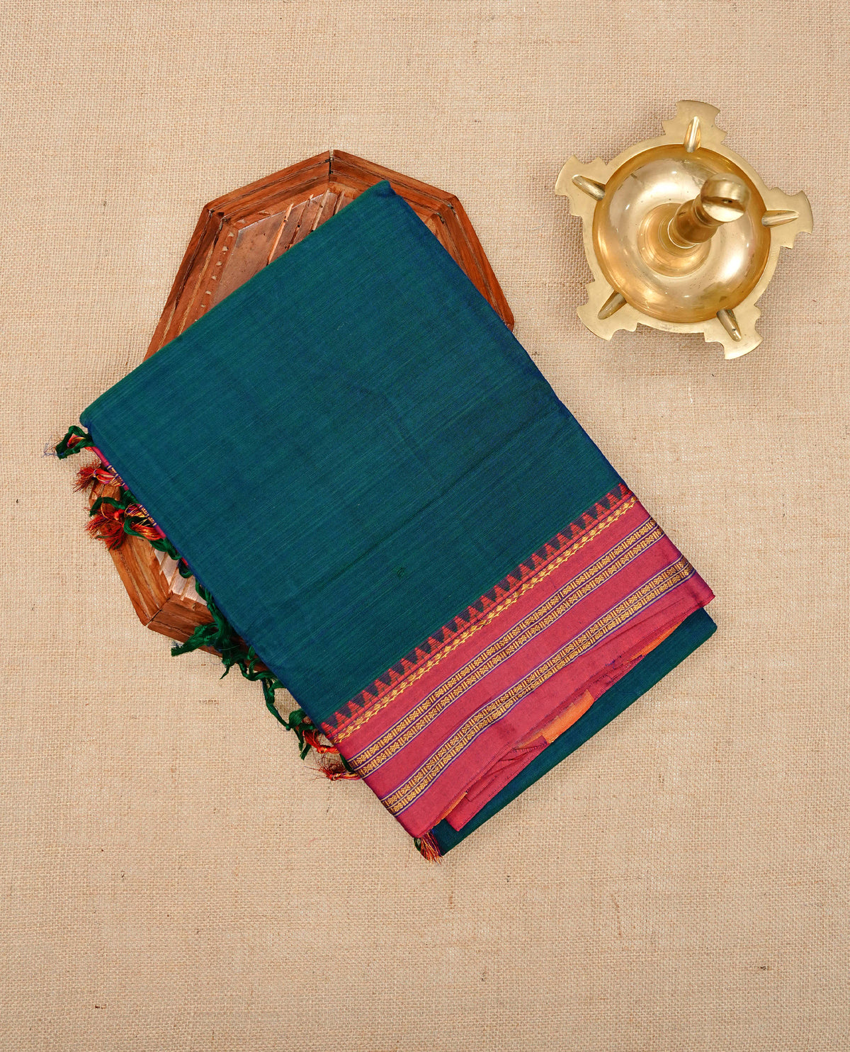 Peacock blue colour Narayanapattu cotton saree with a plain body, complemented by a Red colour with elegant gold zari detailing border & contrast striped pallu, paired with a matching blouse piece.
