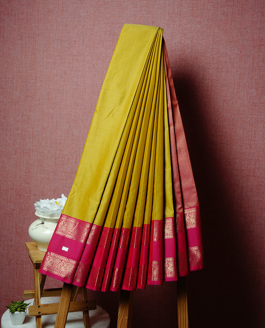 Old gold coloured soft silk saree featuring gold zari stripes and motifs across the body, enhanced with a contrast Magenta border and pallu, paired with a matching contrast blouse piece.