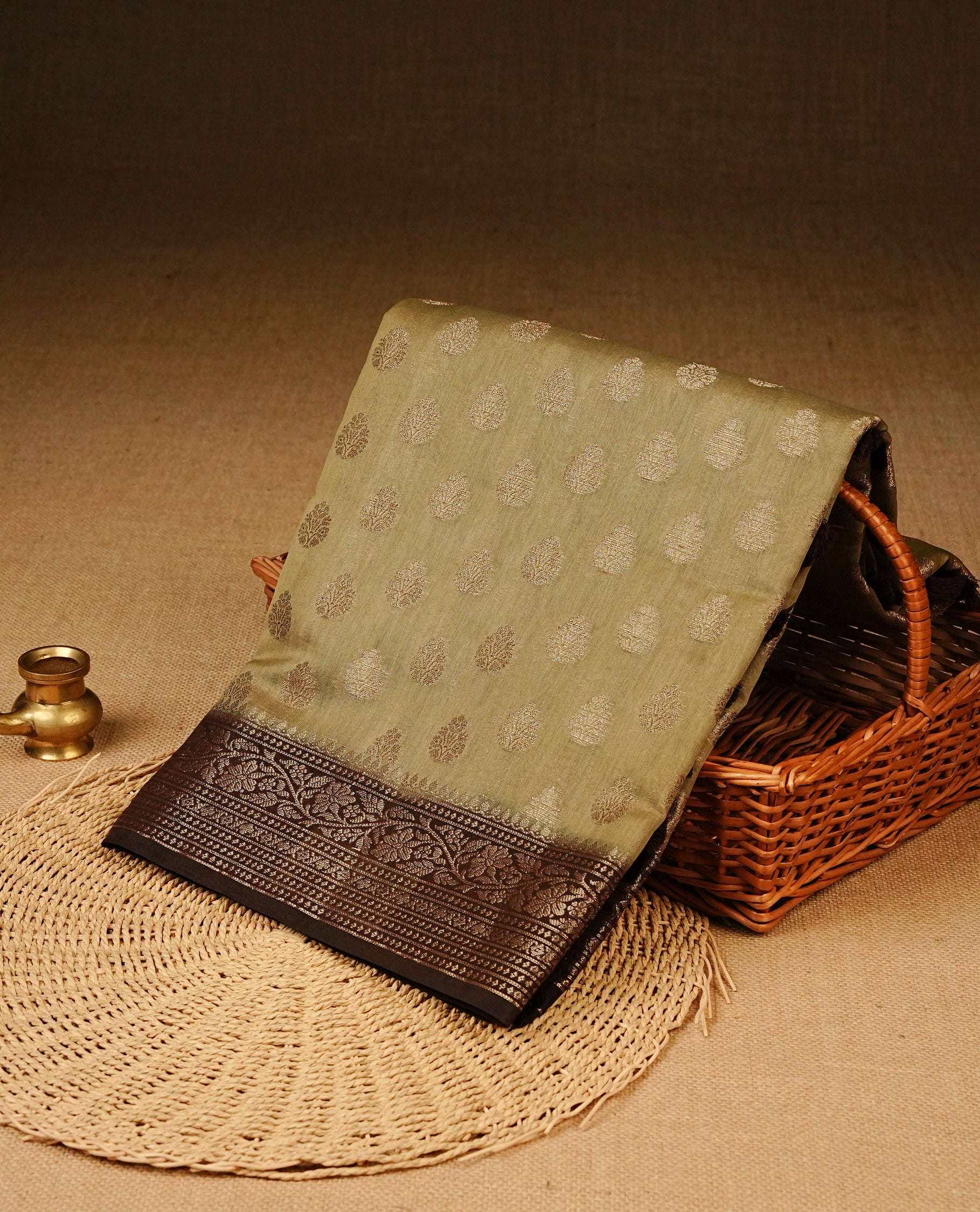 Pastel Olive Colour Tussar Silk saree with antique zari butta motifs On Body, a Brown floral zari border, a rich zari pallu, and a matching blouse piece.