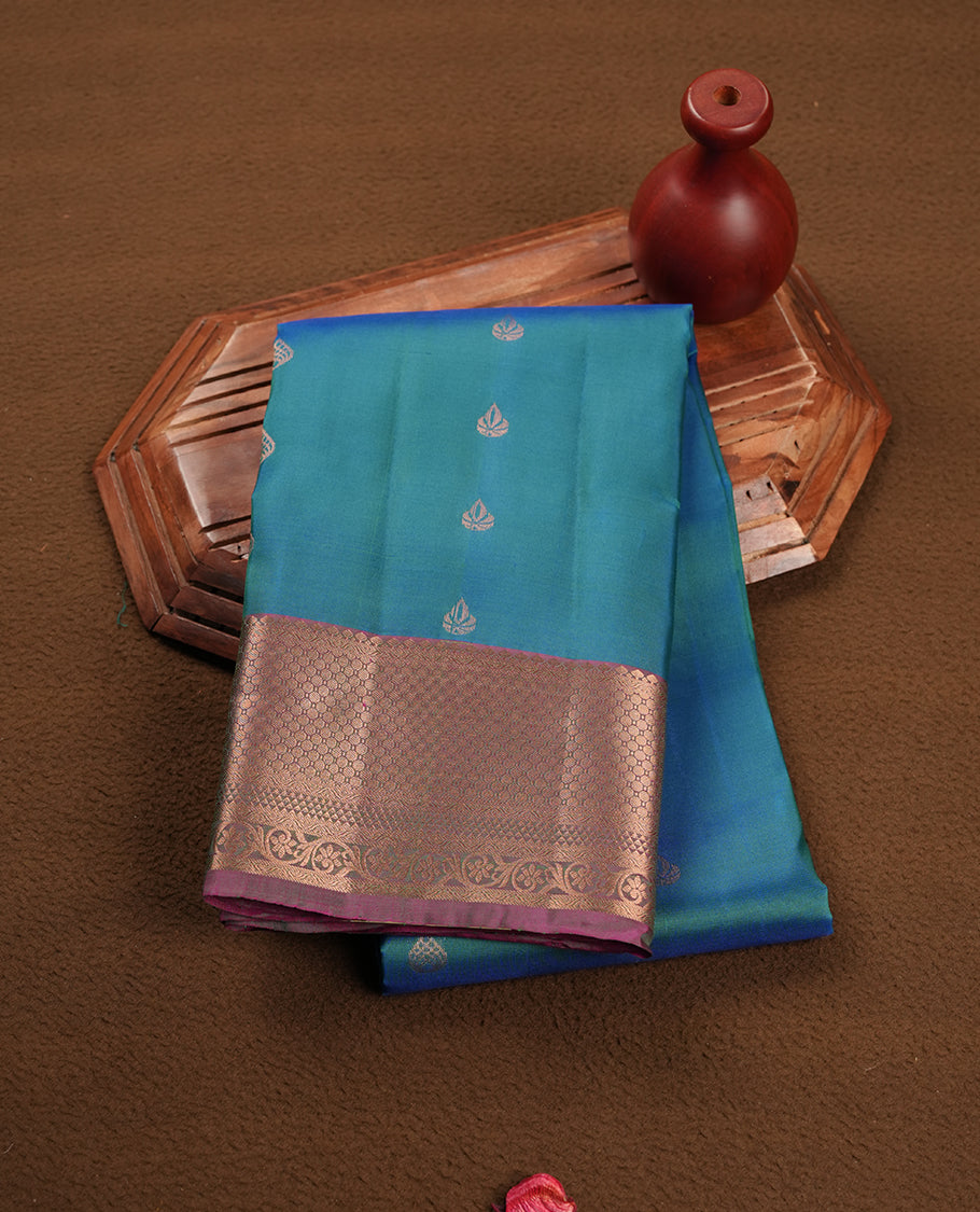 Peacock colour soft silk saree featuring gold zari motifs on the body, complemented by a contrast Magenta traditional zari floral kodi border and pallu, paired with a matching blouse piece.