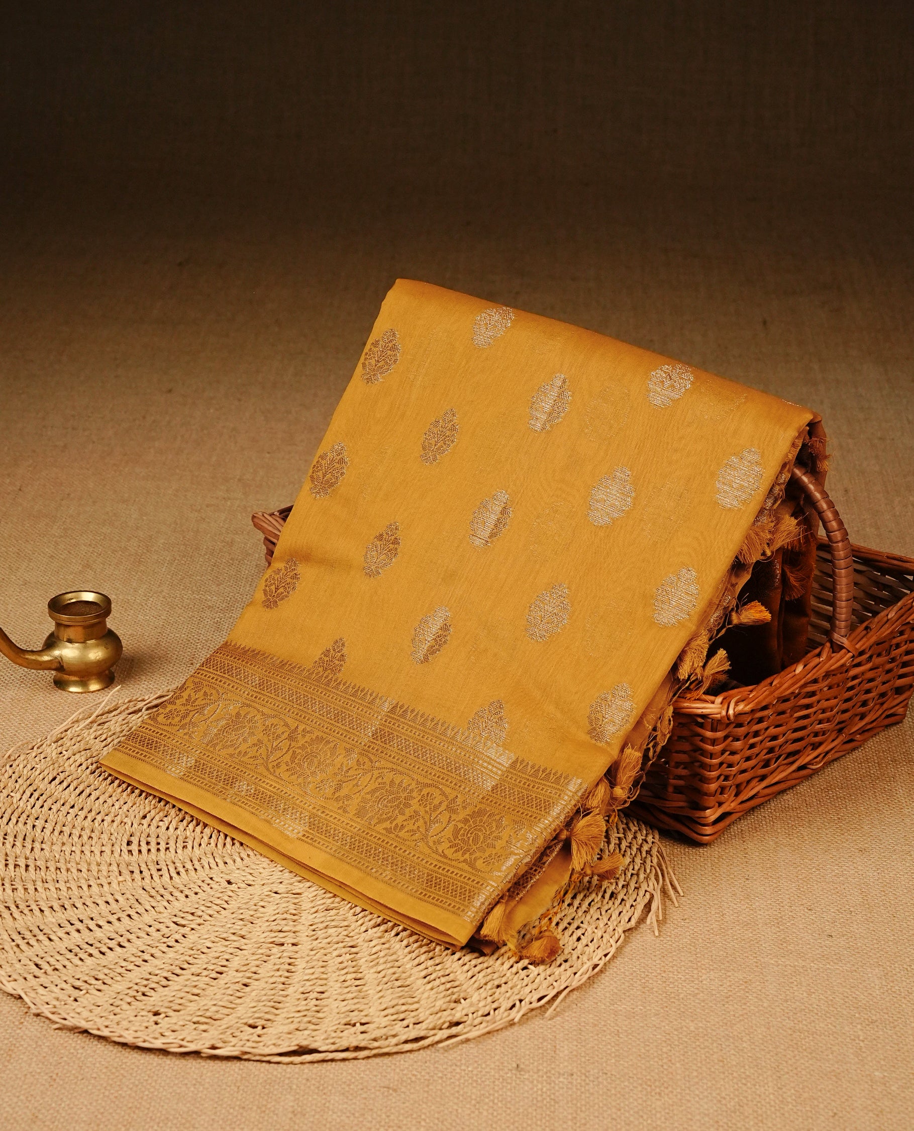 Mustard Yellow colour Tussar Silk saree featuring antique zari butta motifs on the body, enhanced with a self-coloured floral zari border and pallu, paired with a matching blouse piece.