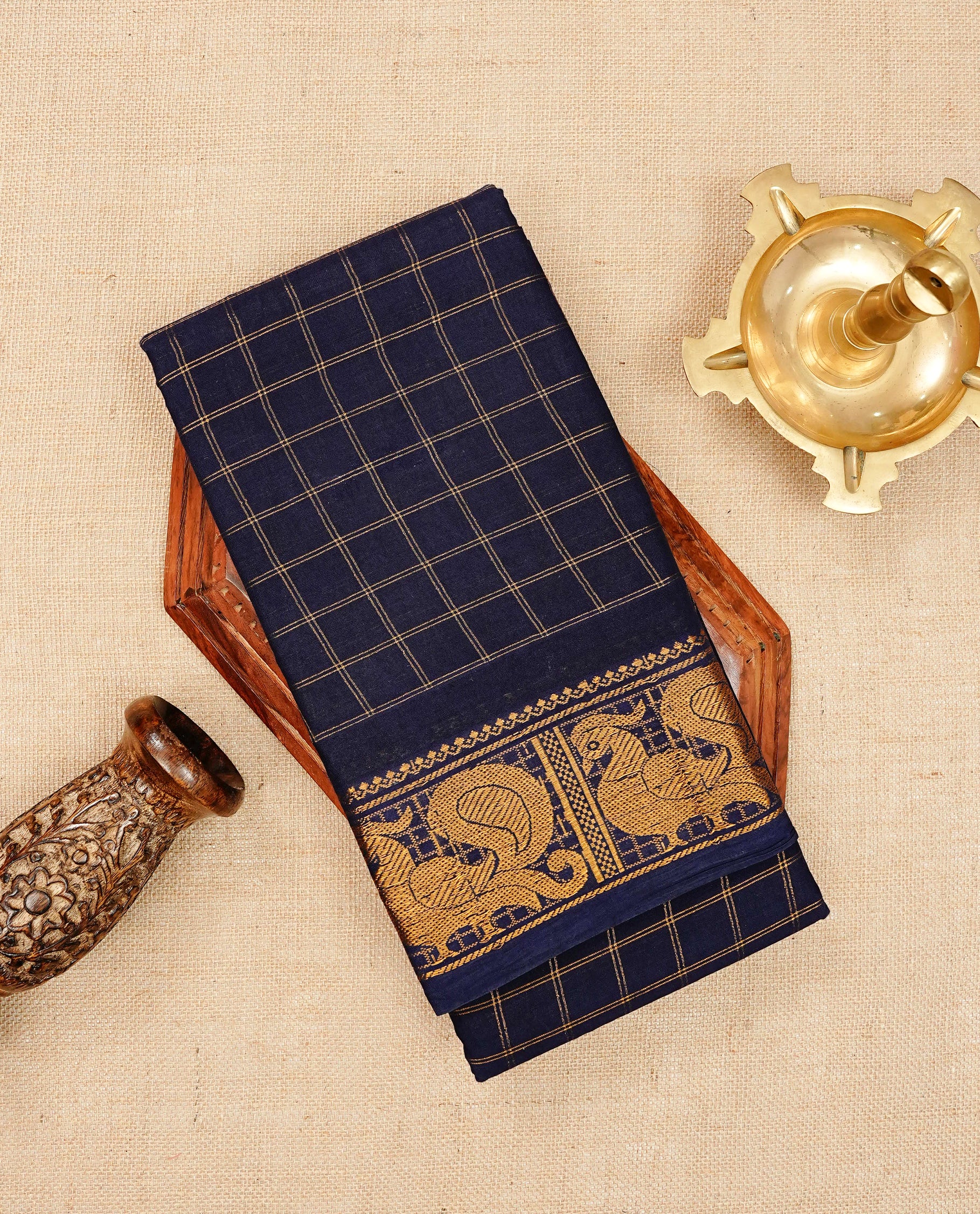 Navy blue Sungudi cotton saree featuring elegant gold zari checks across the body, complemented by a rich gold zari peacock border. Paired with a matching blouse piece