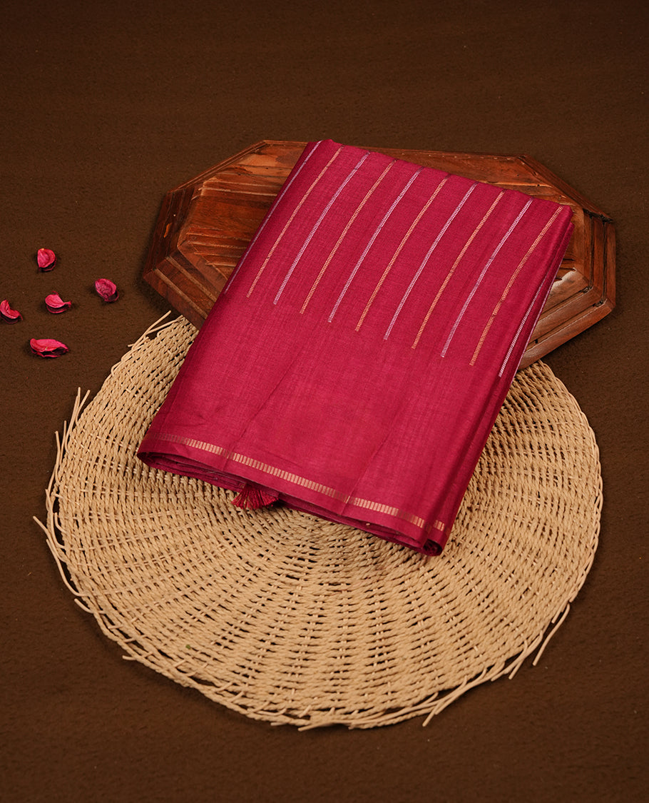 Pinkish Maroon colour semi tussar silk saree highlights gold and silver zari stripes across body, border, pallu and paired with matching blouse piece.