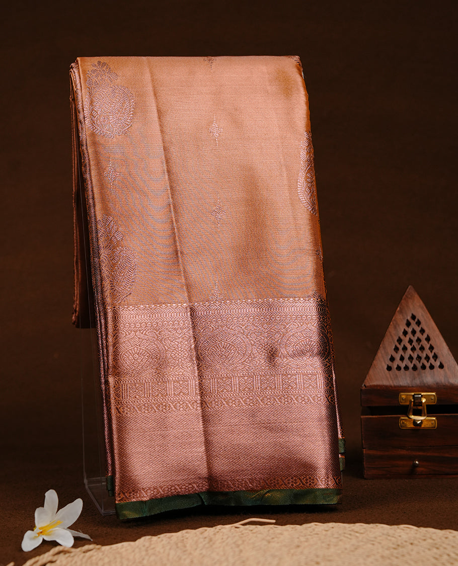 Rose gold colour semi tissue silk saree featuring gold zari motifs on body, self colour with copper zari traditional green simple border, paired with matching blouse piece.