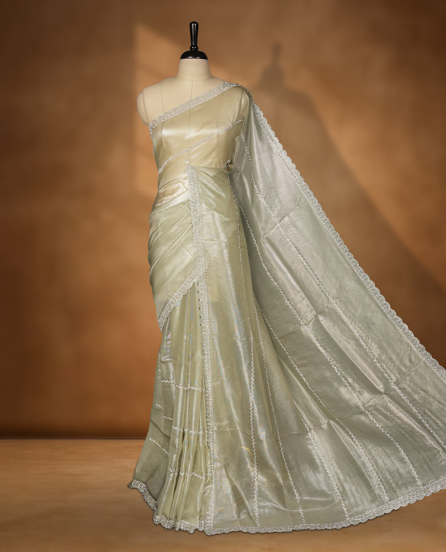 Pastel olive Colour net shimmer fancy saree adorned with strip white stone buttas all over the body, paired with a delicate stone worked border and matching blouse