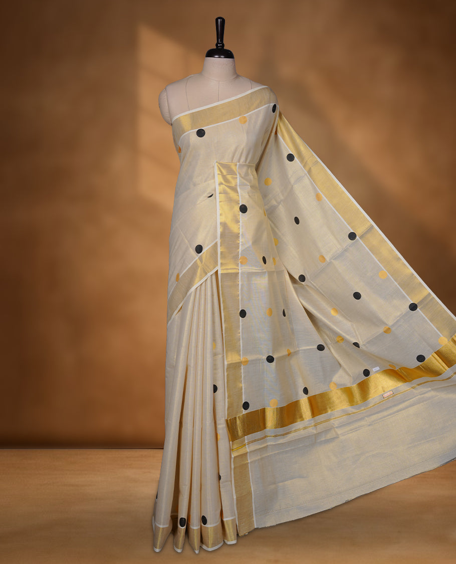 Off-white colour Tissue Kerala saree featuring playful black and gold polka buttas across the body, finished with a classic gold kasavu border and paired with a matching blouse.