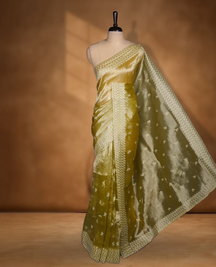 Pastel olive colour organza saree featuring white thread embroidery motifs on body and thread detailing on the border and paired matching blouse.