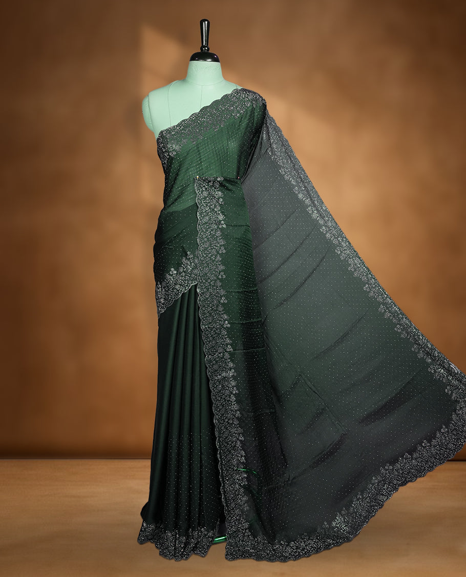 Deep bottle-green chiffon designer saree adorned with delicate white stone work across the body, enhanced with a heavy scalloped stone border and pallu. Paired with a matching stone-detailed blouse.