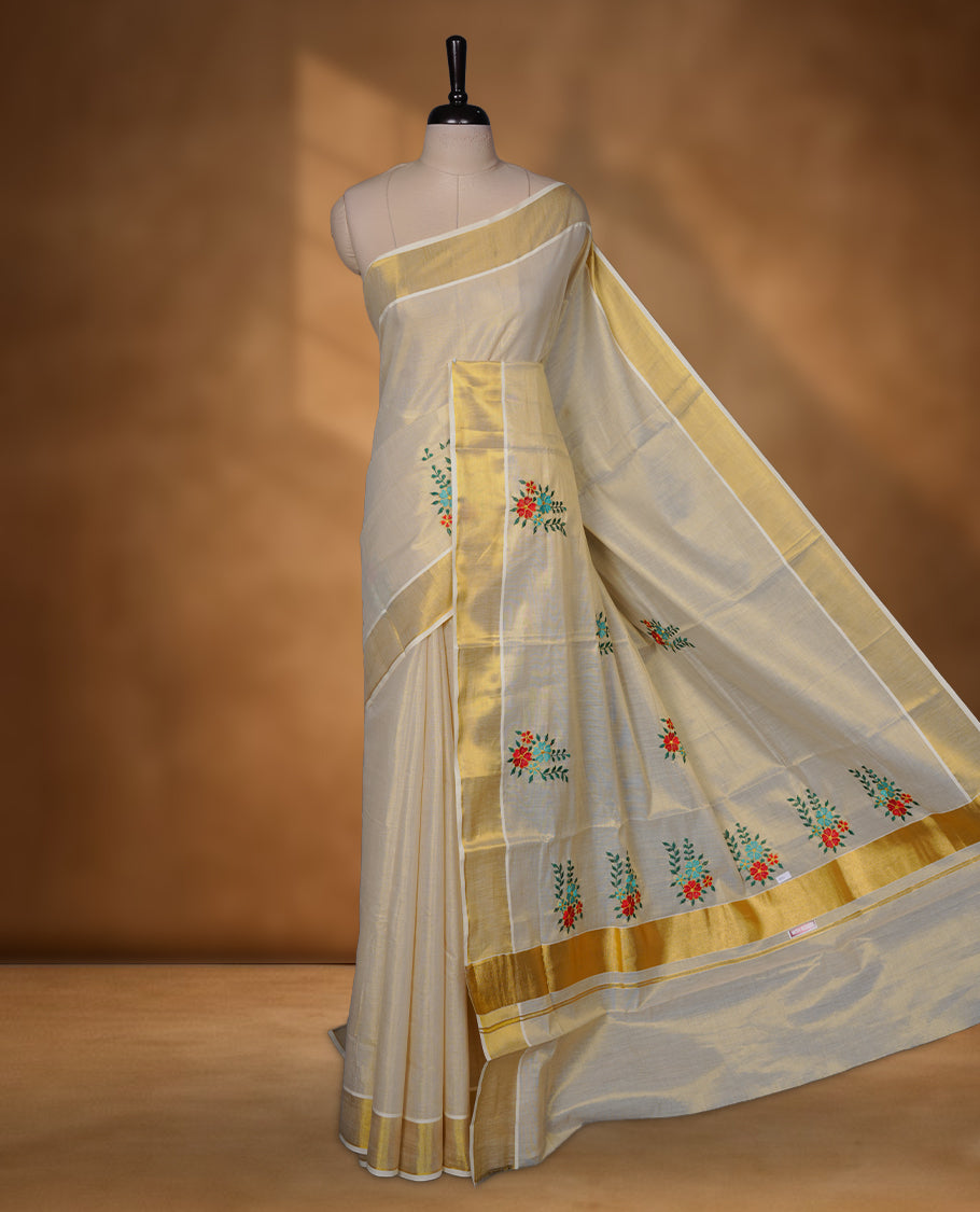 Off-white Kerala kasavu saree with delicate floral embroidery, finished with a classic gold border and paired with a matching blouse.