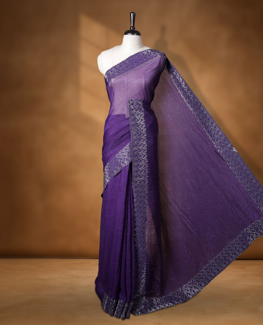 Violet colour chiffon designer saree, featuring white stone all over on body, heavy stone patttern on border and pallu, Paired with matching blouse.