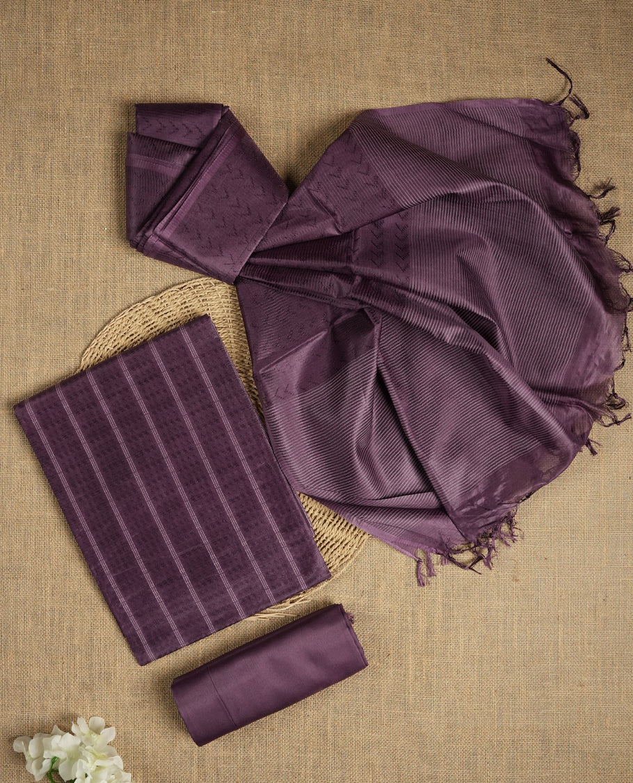Dark lavender tussar suit material featuring a subtle self woven pattern and vertical lines on the body, paired with a lightweight matching dupatta with tassel edges and a plain bottom piece.