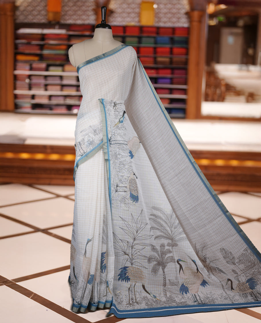 Off white colour Soft cotton saree featuring elegant bird prints along the edges, a stylish checked body, and a beautifully designed blue border & Paired with a matching blouse piece.