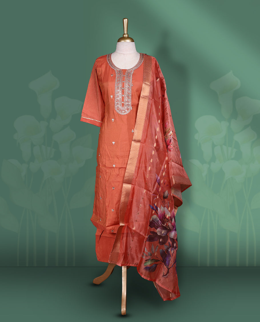 Pinkish Orange colour churidar set featuring elegant gold thread embroidery on the neckline, sleeves, and scattered motifs across the body, Paired with a matching embroidered & floral printed pattern dupatta