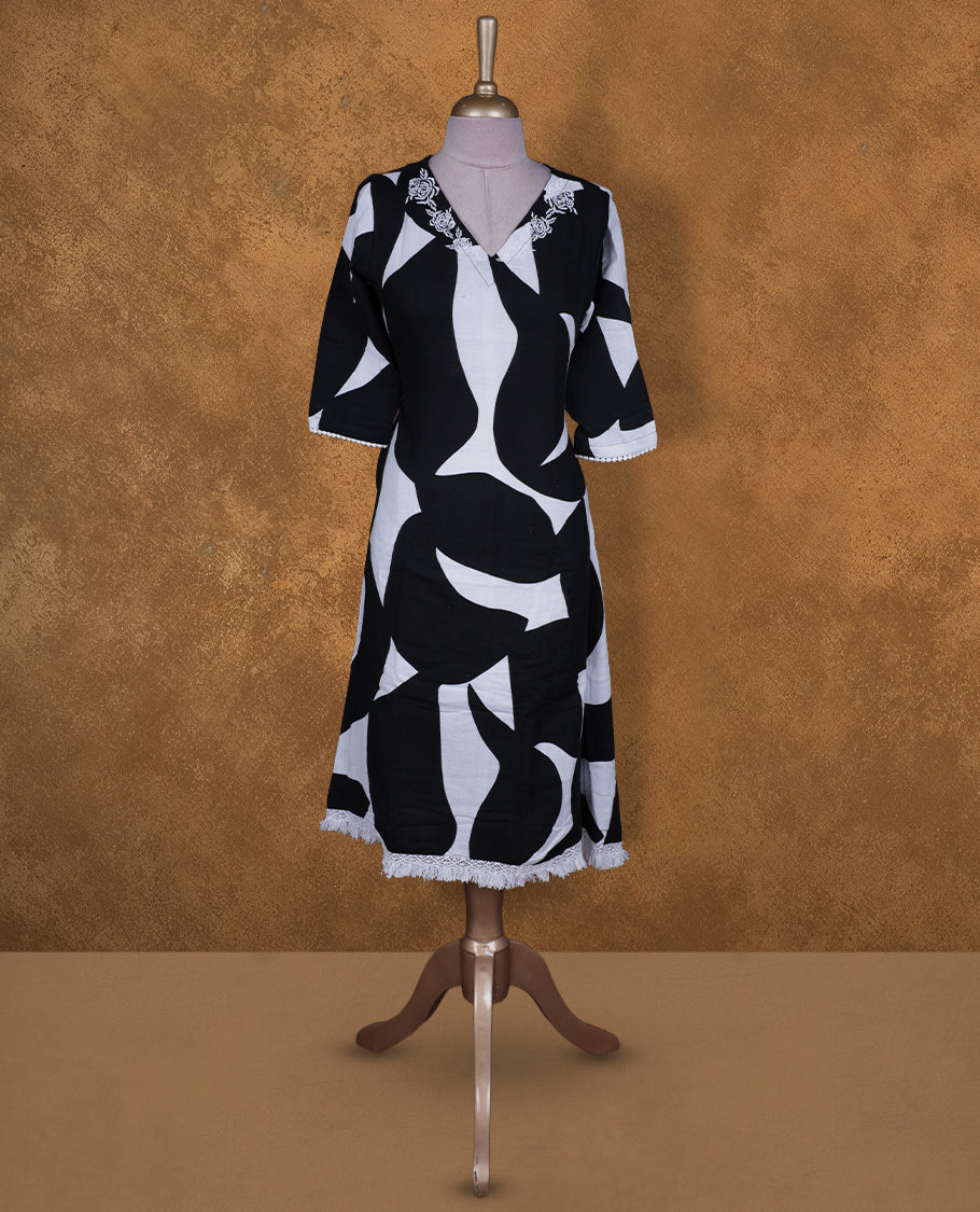 Black and white colour abstract printed kurti by Talisha with V neckline, floral neck embroidery, A‑line knee‑length silhouette, elbow‑length sleeves, and fringe lace at the hem.