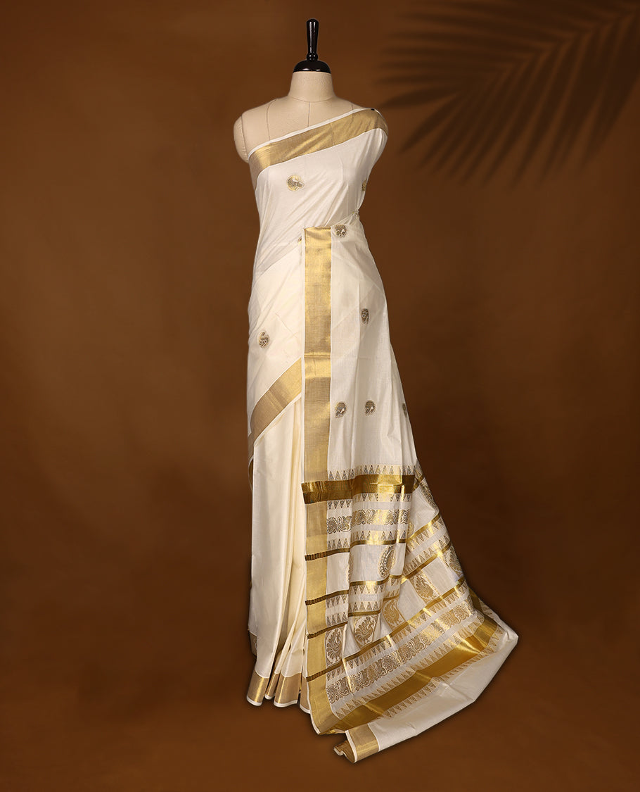Graceful Kerala Kasavu saree with golden zari motifs and richly woven pallu, the ivory base and elegant border make it perfect for festive and traditional occasions, Pair with temple jewelry for a classic look.