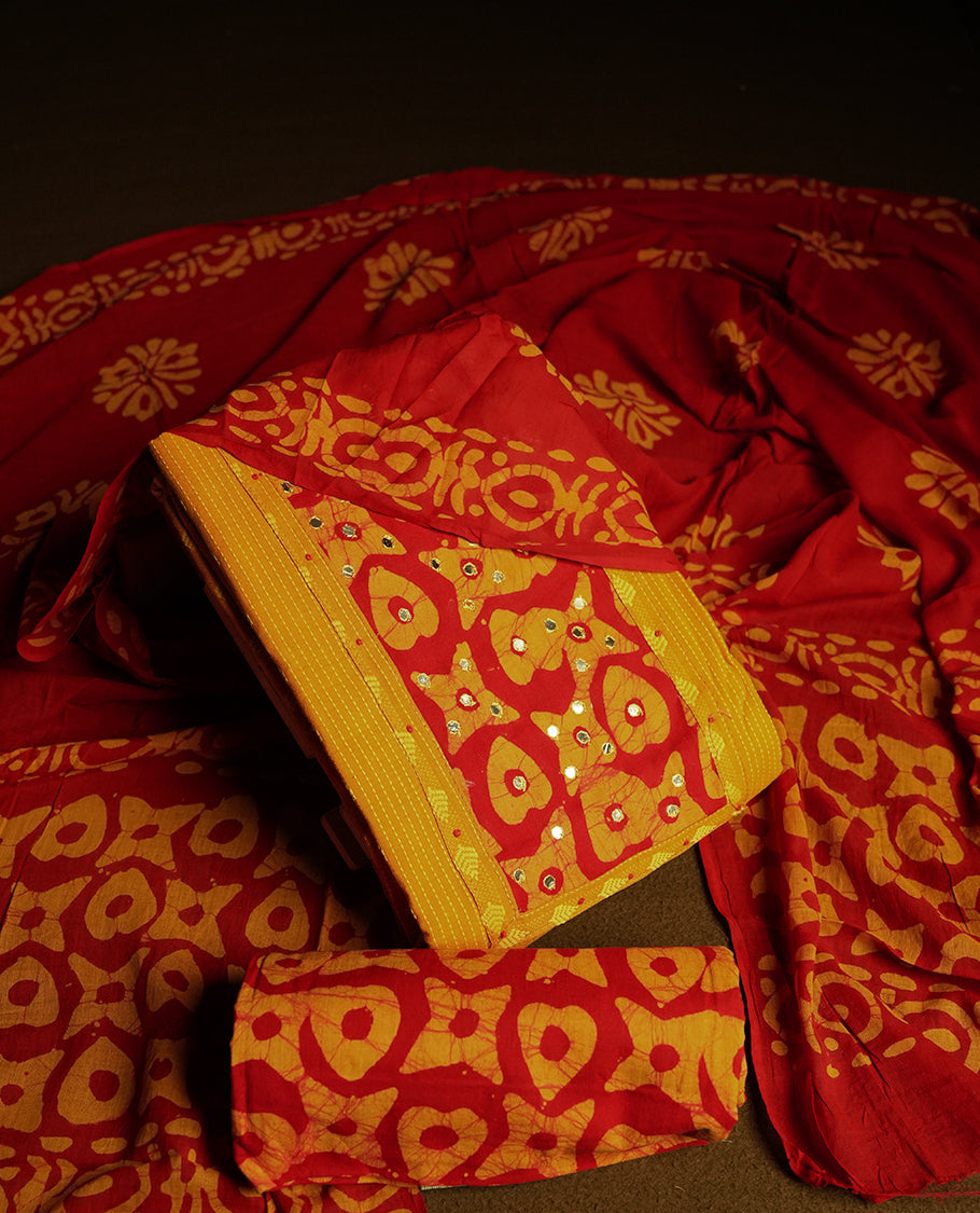 Maroon and Yellow cotton churidar material adorned with mirror work on the neckline, featuring traditional tie dye patterns & Comes with a matching printed dupatta and coordinated printed fabric for the bottom.