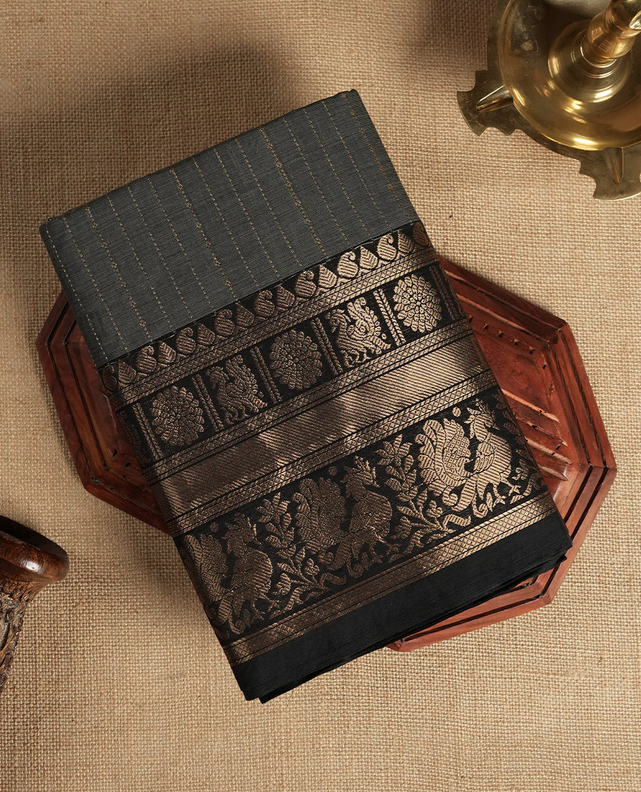 Grey colour Chettinad cotton saree featuring fine golden zari lines on the body, The contrasting black border is richly woven with intricate zari floral and paisley motifs & Comes with a matching blouse piece.