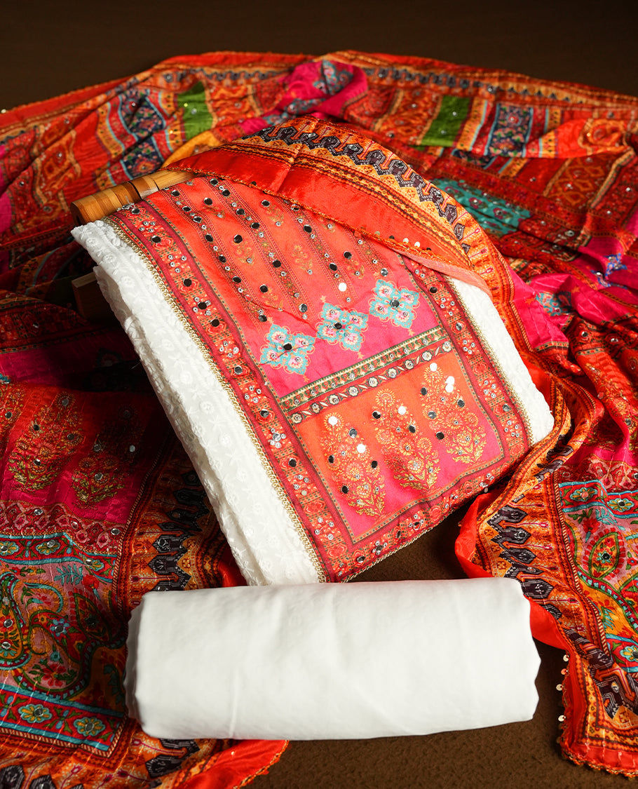 White colour churidhar material featuring Mirror and thread embroidery & foral print pattern on the contrast Dark orange colour front panel, floral digital printed dupatta with elegant border, and matching plain bottom