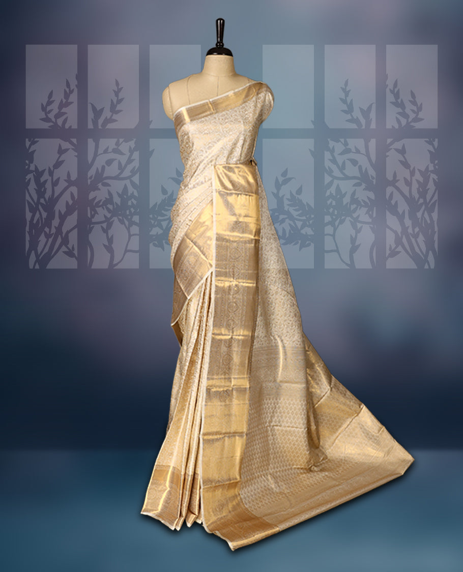 Ivory gold semi silk brocade saree with rich self brocade detailing across the body, paired with an opulent gold woven border and pallu. Comes with a matching blouse for a timeless traditional look.