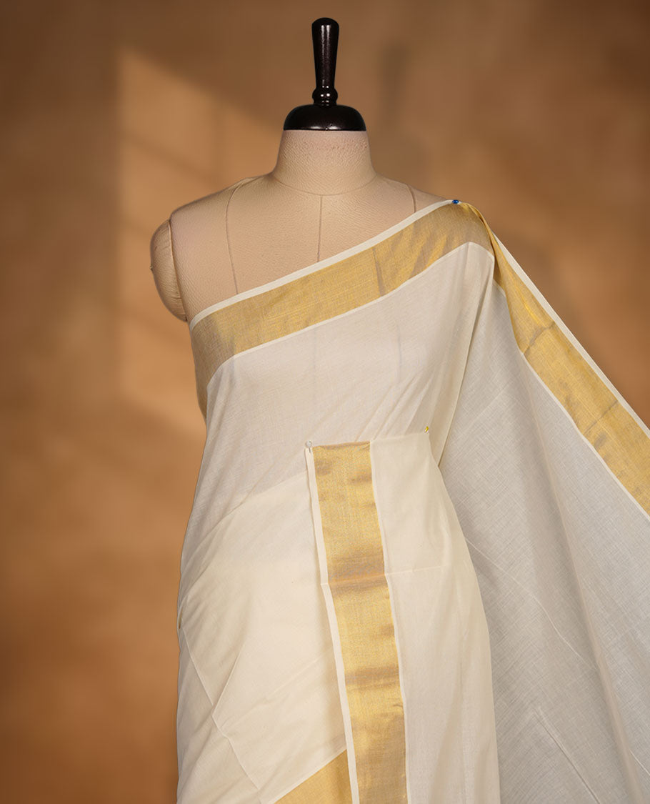 Off-white colour cotton Kerala saree crafted in a soft, sheer weave, finished with a classic gold kasavu border along the body and pallu, and paired with a matching blouse.