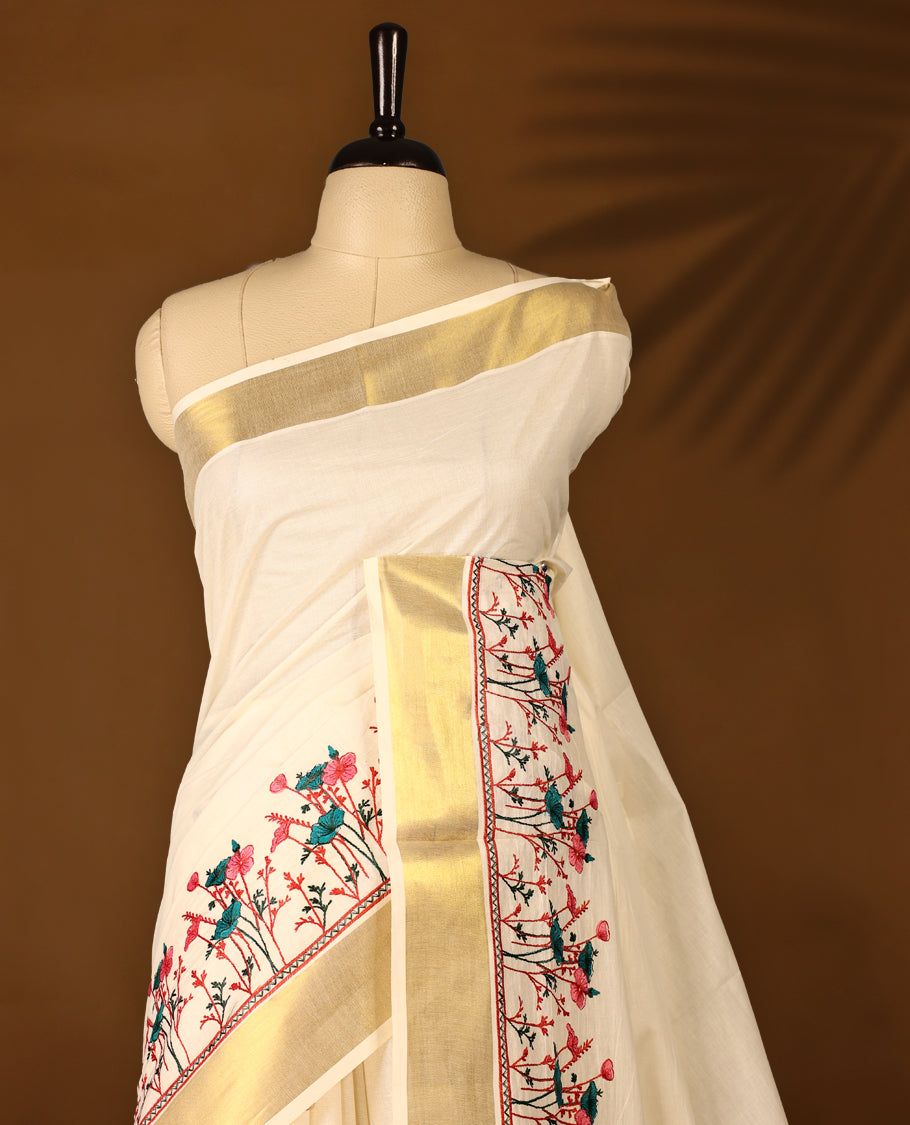 Light Gold colour Cotton Kerala saree featuring Plain body and a beautifully woven Gold Kasavu border with Heavy Green and Pink colour Floral embroidery work, paired with a matching blouse perfect for festive occasions.