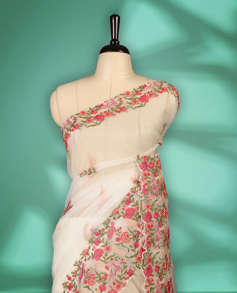 Off white colour organza saree featuring delicate floral and bird themed embroidery with scalloped edges on the border and pallu, lending a graceful charm. Paired with a matching blouse.
