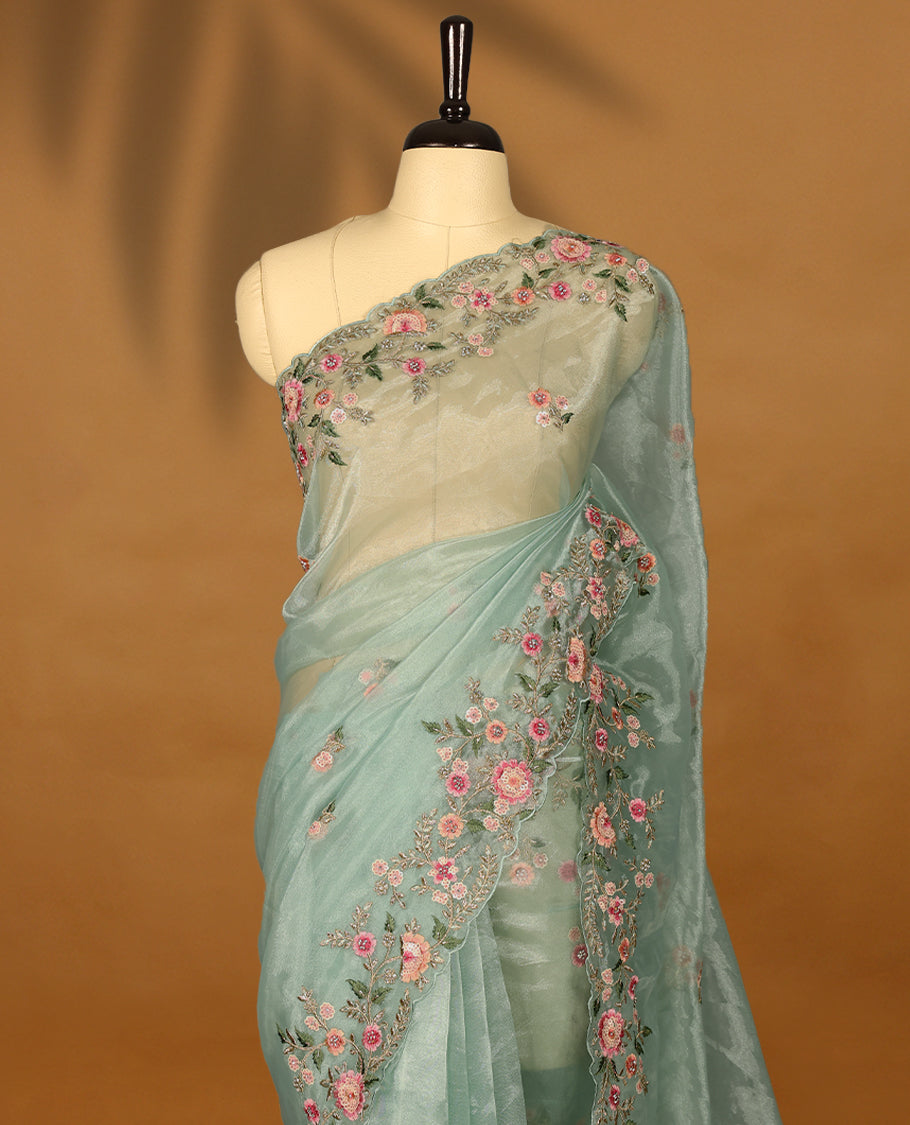 Pastel Aqua Organza Tissue Silk Saree is beautifully adorned with intricate pink floral embroidery Border and a matching blouse.