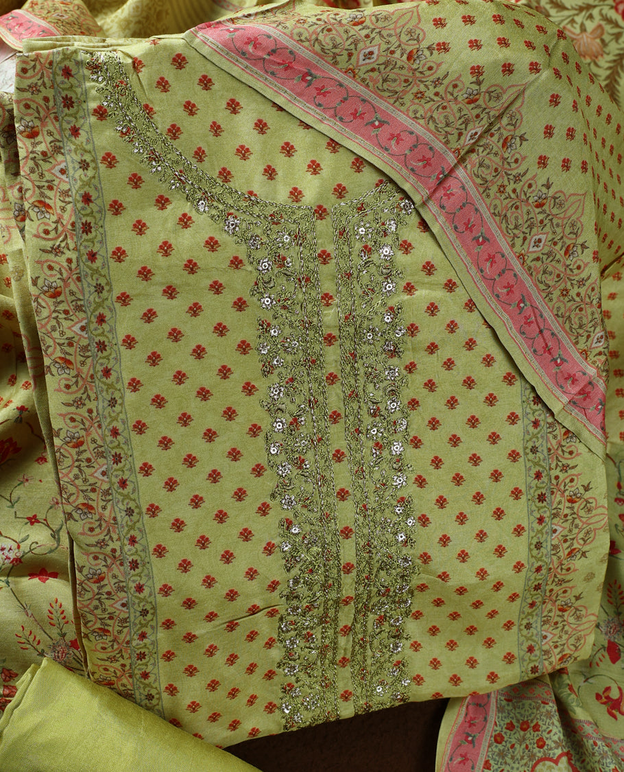 Olive green colour churidhar material adorned with subtle red prints and intricate embroidery on the neckline, paired with a beautifully printed dupatta and plain matching bottom.