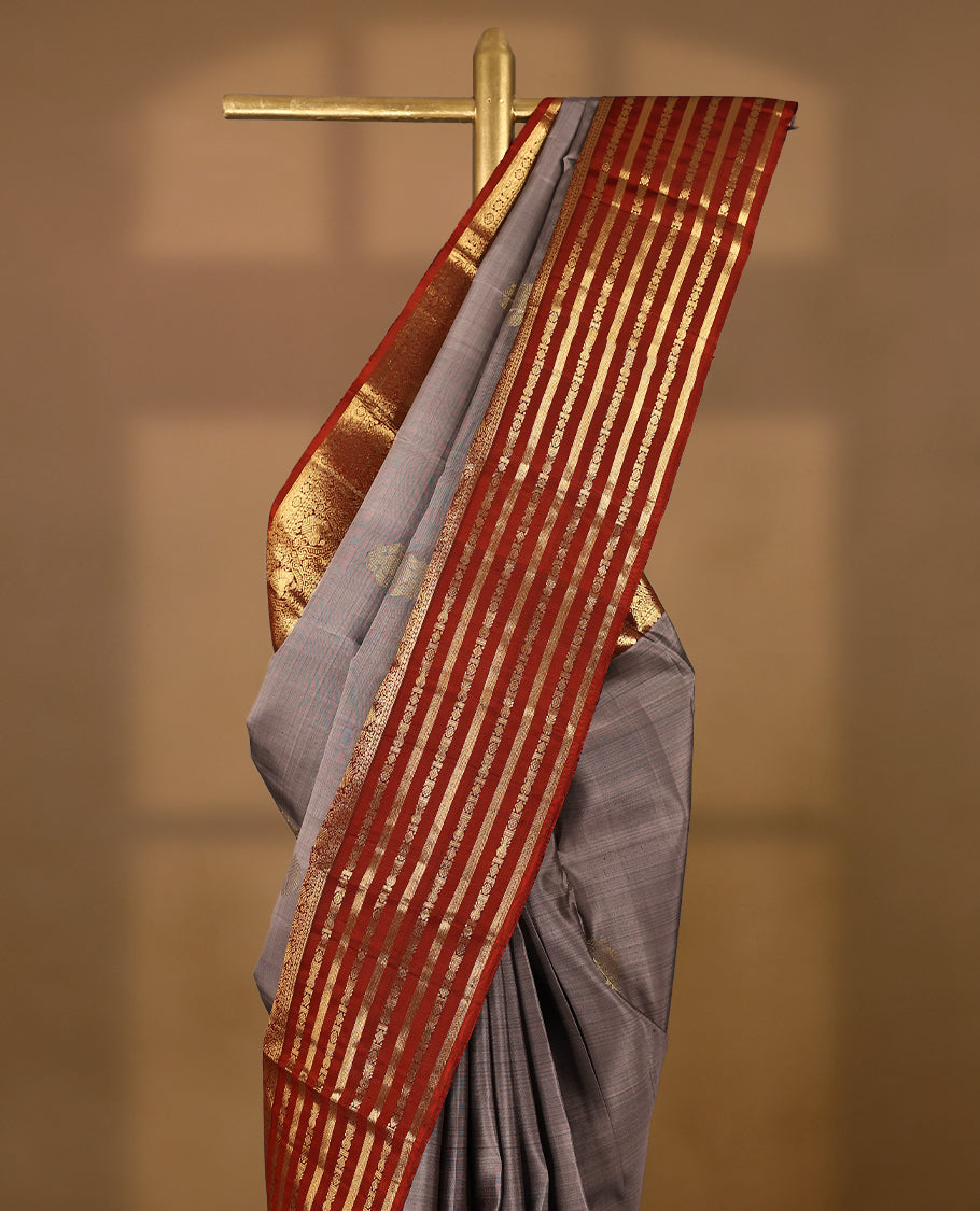 Muted lavender-grey Colour traditional Kancheepuram silk saree adorned with antique zari double peacock motifs on the body, rust red traditional border with alternating horizontal gold zari stripes and ornamental weaving , with a matching blouse.