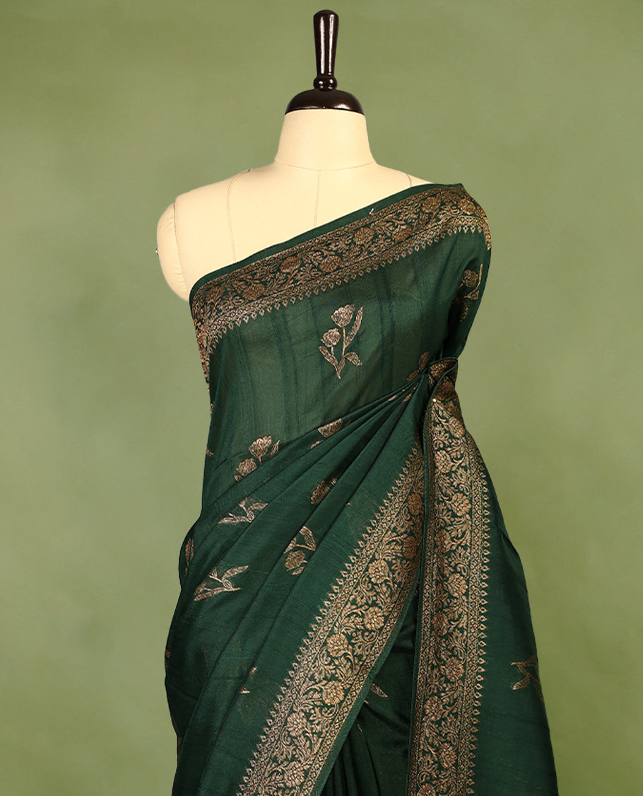 Dark Green colour semi Banaras tussar georgette saree embellished with antique zari flower motifs across the body, complemented by a rich Banaras border and paired with a matching blouse.