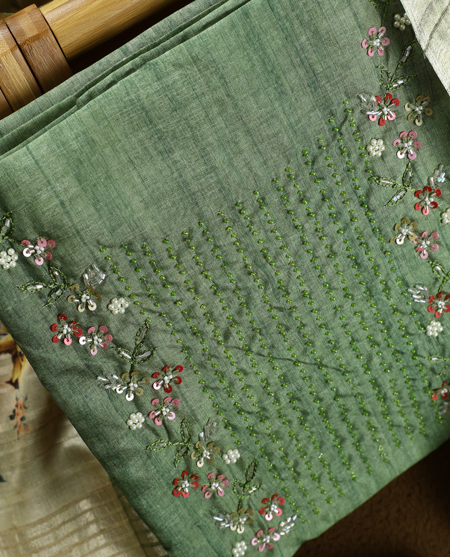 Light green colour churidhar material adorned with floral embroidery and sewn glass beads on the yoke, paired with a plain green bottom and a beige dupatta featuring floral prints.