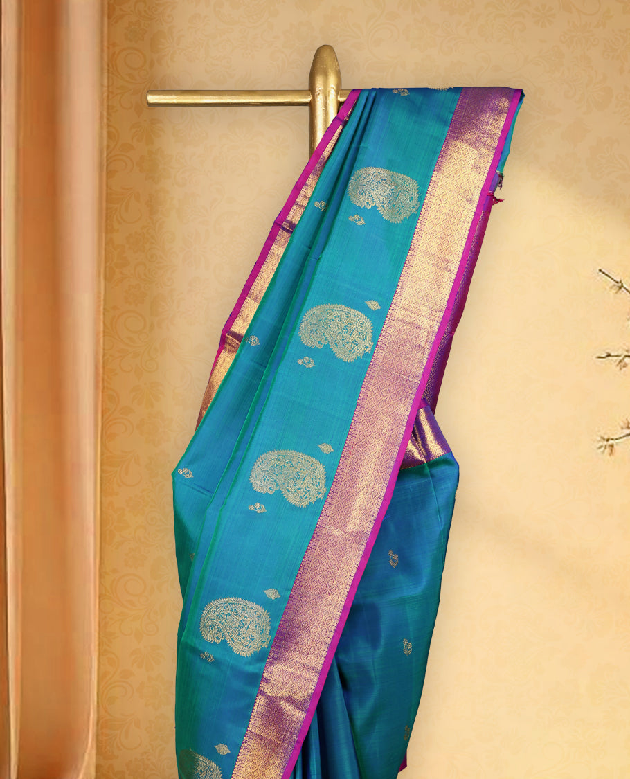 Peacock blue colour pure Kancheepuram saree with gold zari paisley mango motifs on the body traditional border with diamond pattern and purple piping grand pallu paired with matching blouse