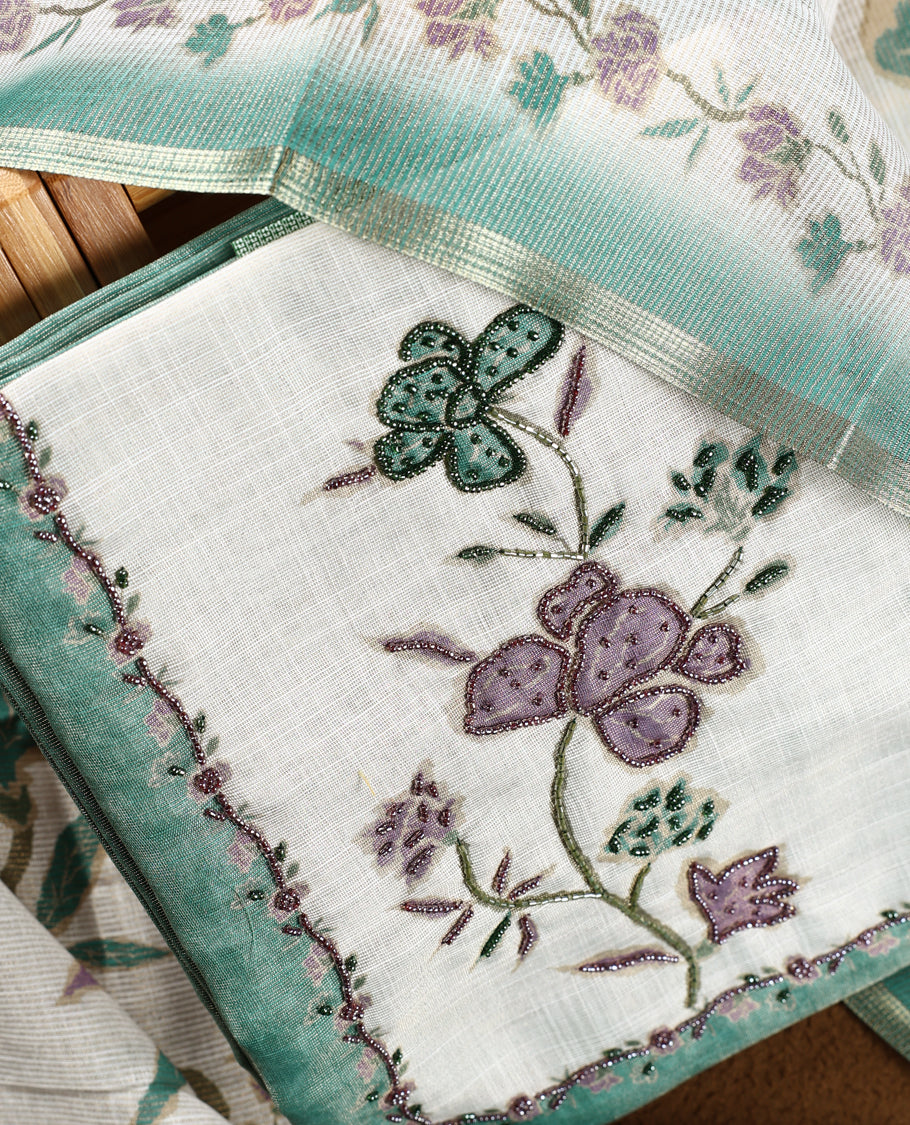 Beige & Sea green colour churidhar material with floral print enhanced by sewn glass beads on the body, paired with plain lavender bottom & floral print dupatta.
