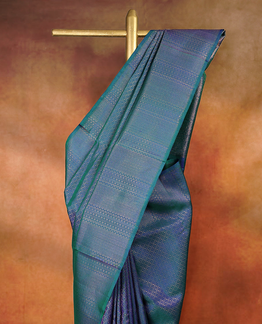 Peacock blue and green dual tone pure Mayuri silk saree featuring intricate gold Zari woven patterns across the body, highlighted with a rich geometric woven border, with matching blouse
