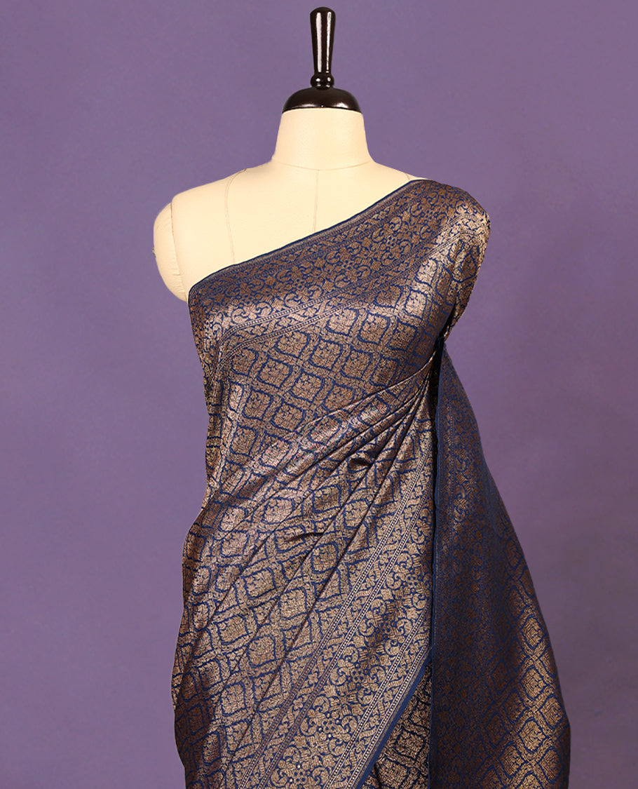Navy Blue colour semi Banaras Katan saree featuring an antique Gold zari jacquard body, complemented by a self colour traditional border with a floral kodi design, paired with a matching blouse
