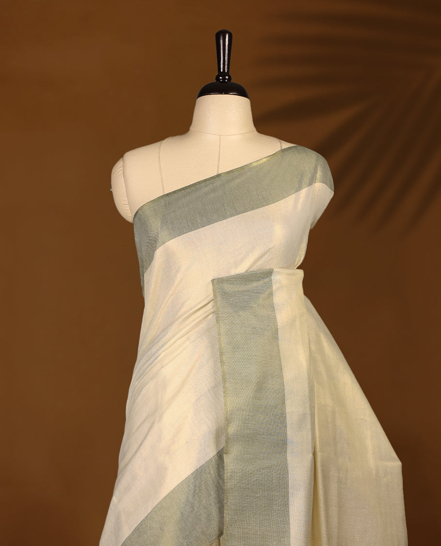 Elegant light gold Colour soft tissue Kerala saree featuring a plain body, muted green zari border, and a striking green woven checkered pallu, paired with a matching blouse.