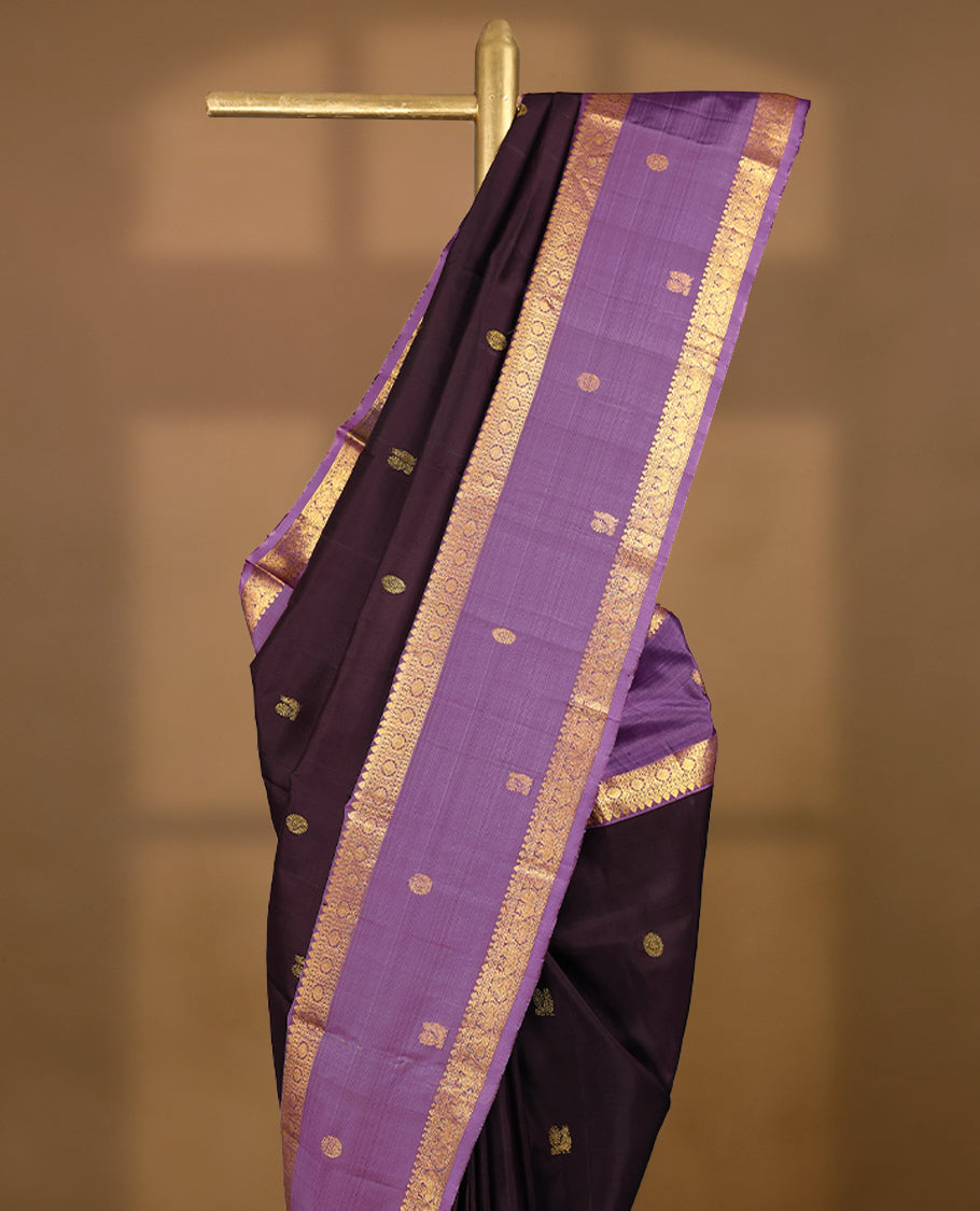 Dark chocolate Colour pure traditional Kancheepuram silk saree adorned with antique zari Chakkram motifs on the body, beautifully complemented by a contrasting traditional border, and paired with a matching blouse.