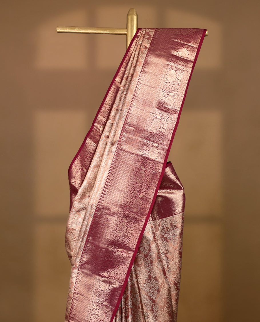 Pastel maroon Colour Kancheepuram tissue silk saree adorned with intricate silver floral zari work on the body, beautifully highlighted by a maroon traditional Rudraksham and floral design border, and paired with a matching blouse.